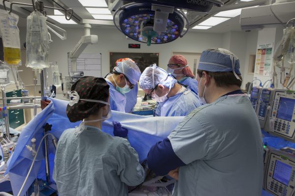 Surgeons in scrubs in an operating room performing open-heart surgery