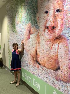 Girl standing in front of a baby mosaic