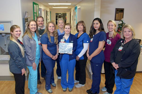 Group of nurses in scrubs smiling and holding silver Beacon award