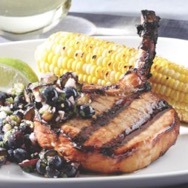 Teriyaki pork chops with blueberry-ginger relish and corn on a white plate