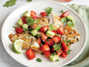 Chicken cutlets with strawberry-avocado salsa on a white plate
