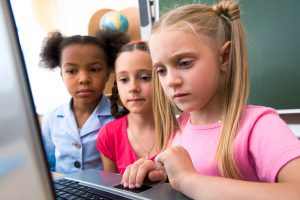 Three children studying a computer screen.