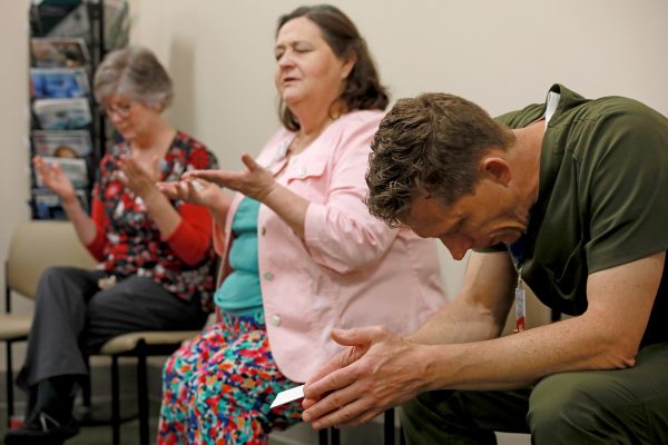 A man and two women sitting and praying