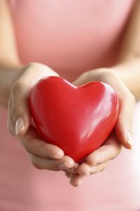 Image of person in a pink dress holding a heart in their hands