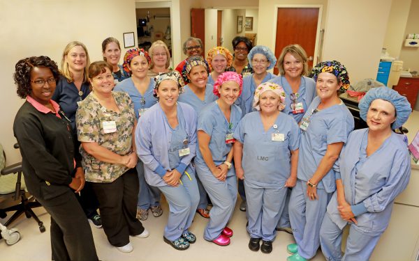 Image of nurses standing together dressed in scrubs and smiling