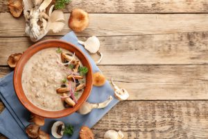 Brown bowl with mushrooms on a wood surface and blue cloth