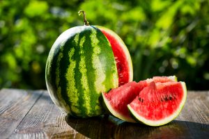 Whole, cut watermelon with 2 slices beside it