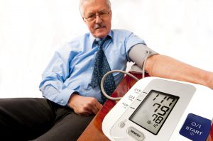 Man in a blue shirt checking his blood pressure using a blood pressure machine