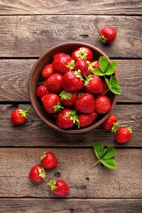 Bowl of strawberries on a wood surface