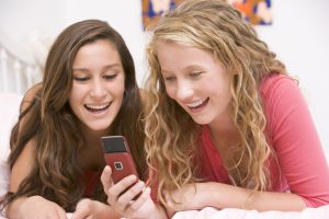 Two girls laughing at a phone screen.
