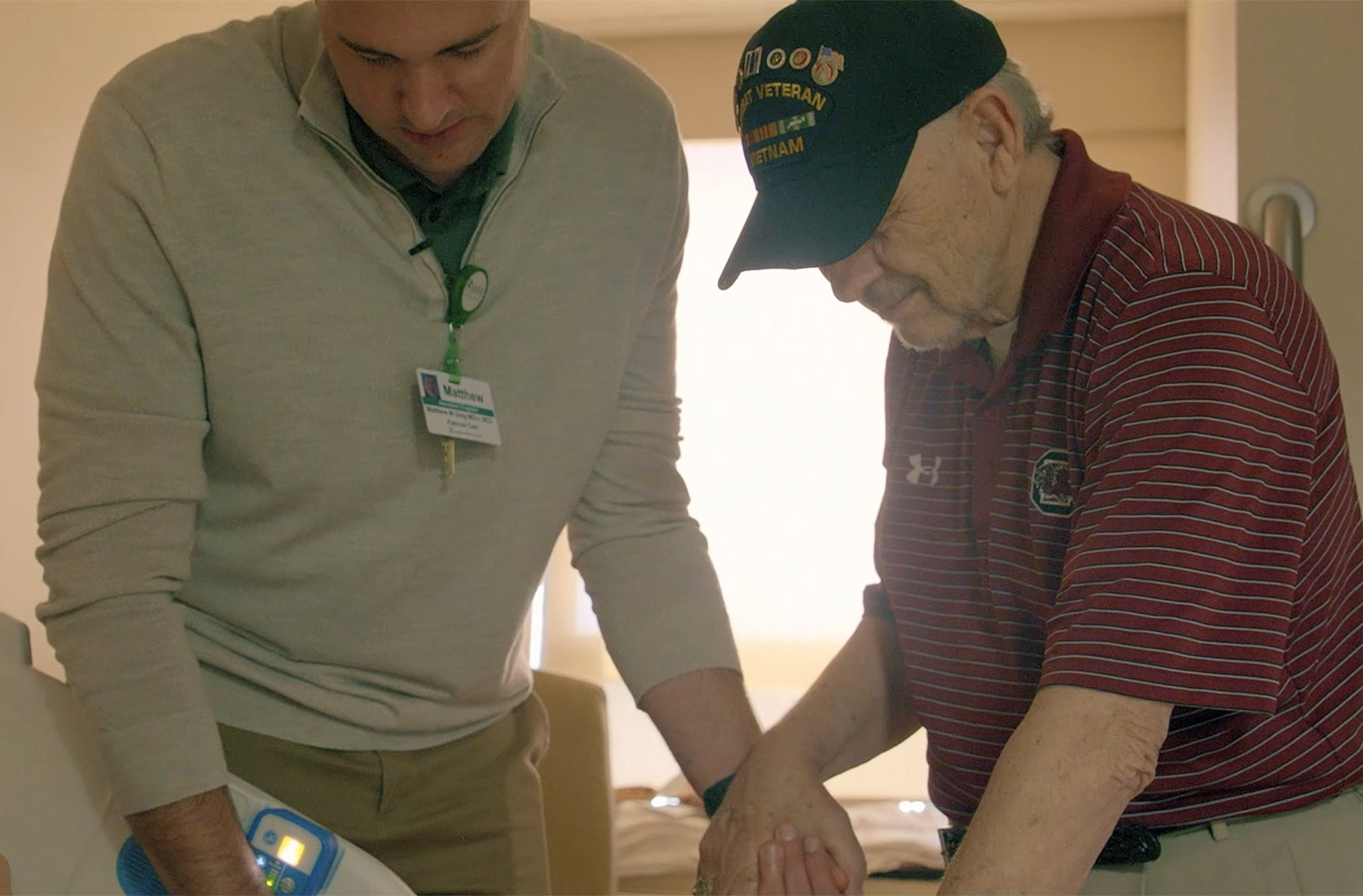 Chaplain praying with family member at patient's bedside