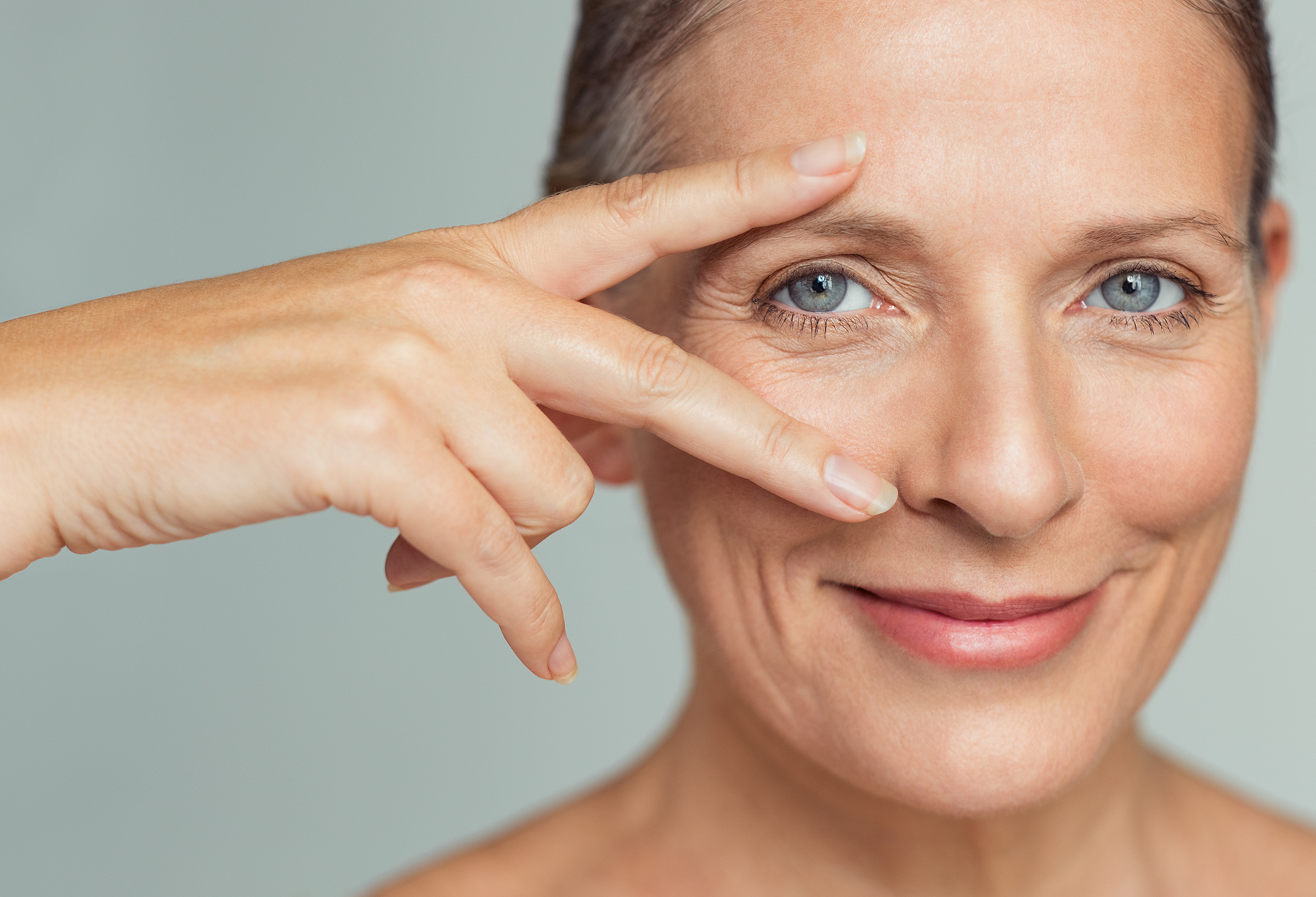 Middle aged women with blue eyes holding her fingers near her eye