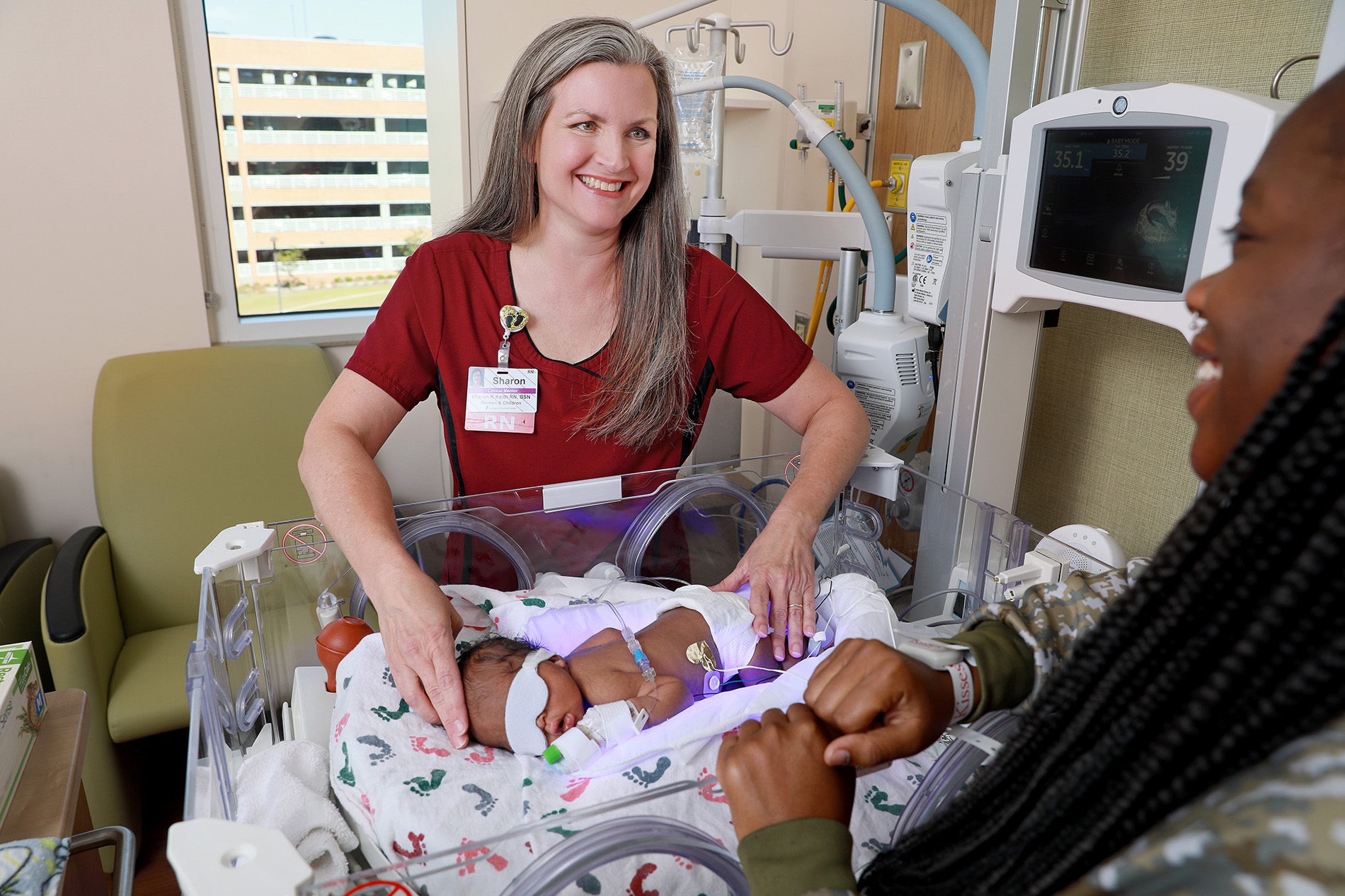 Photo of nurse with baby and mom in Special Care Nursery