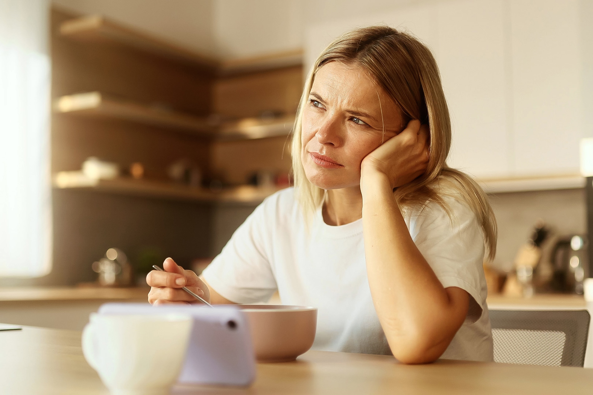 Middle-aged tired woman sitting at kitchen table