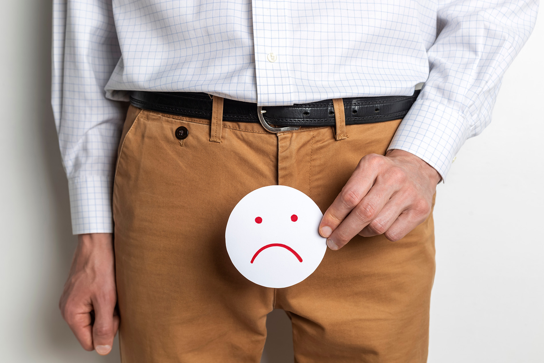 Man holding frowny face sign in front of pants