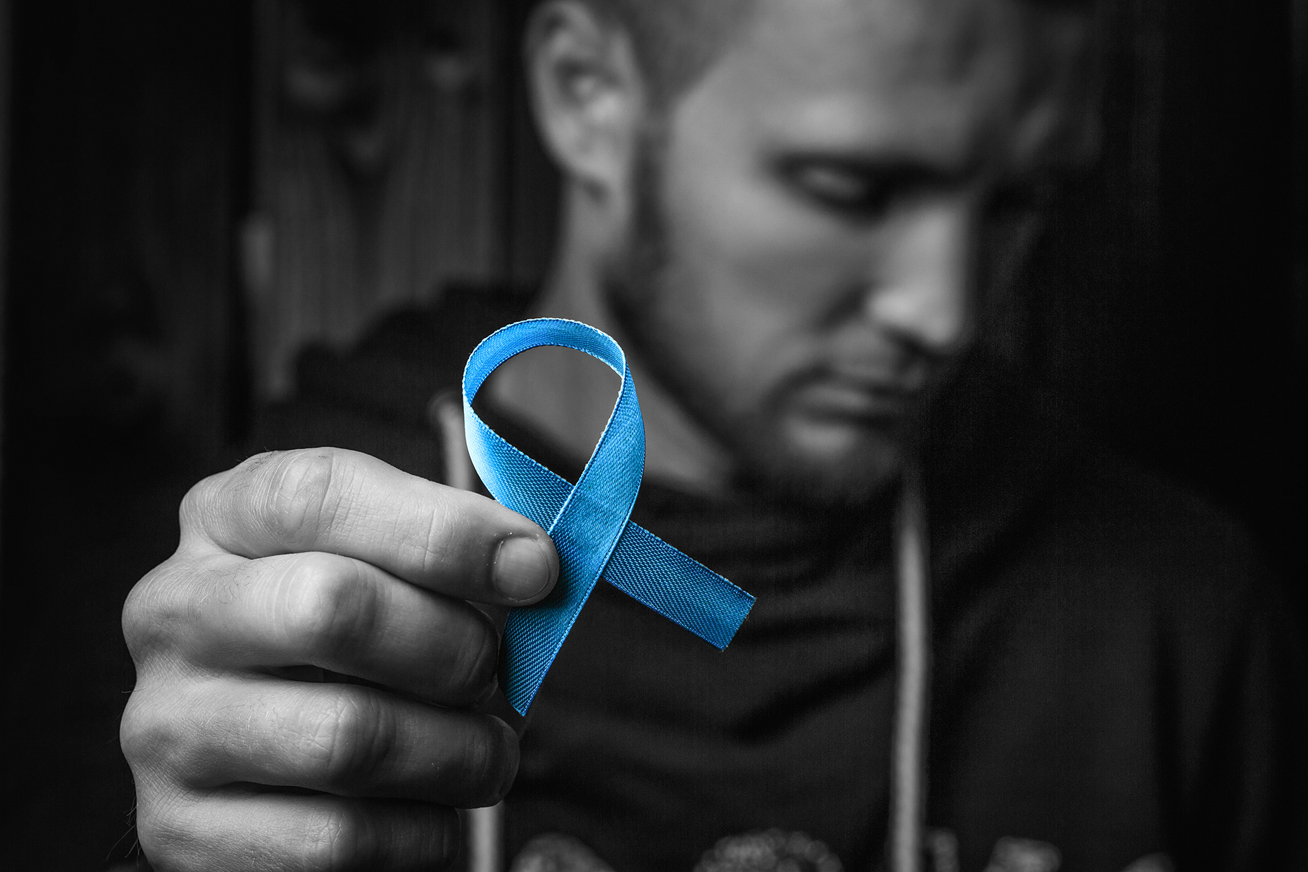 Young man holding blue colon cancer awareness ribbon