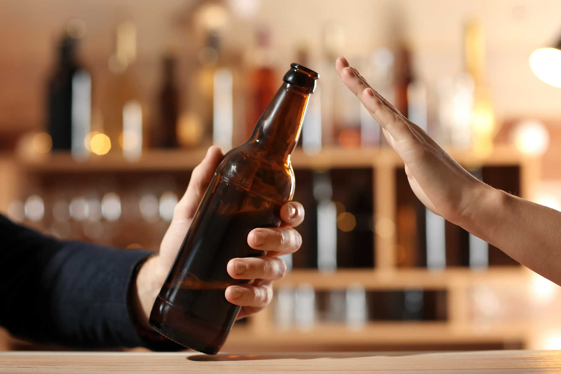 Woman holding up her hand to refuse a beer offered to her