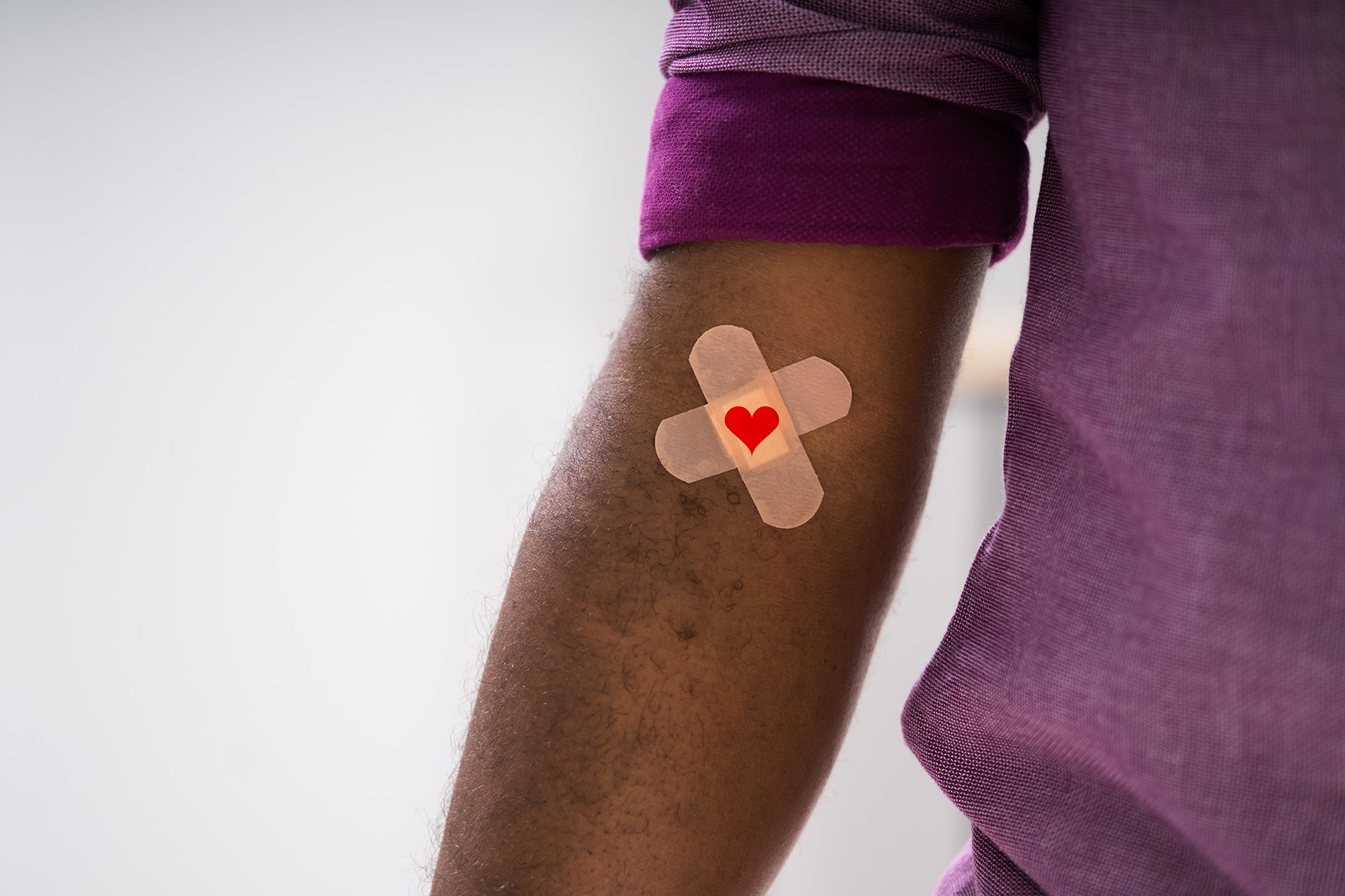 Black male in purple shirt with bandage on arm after donating blood
