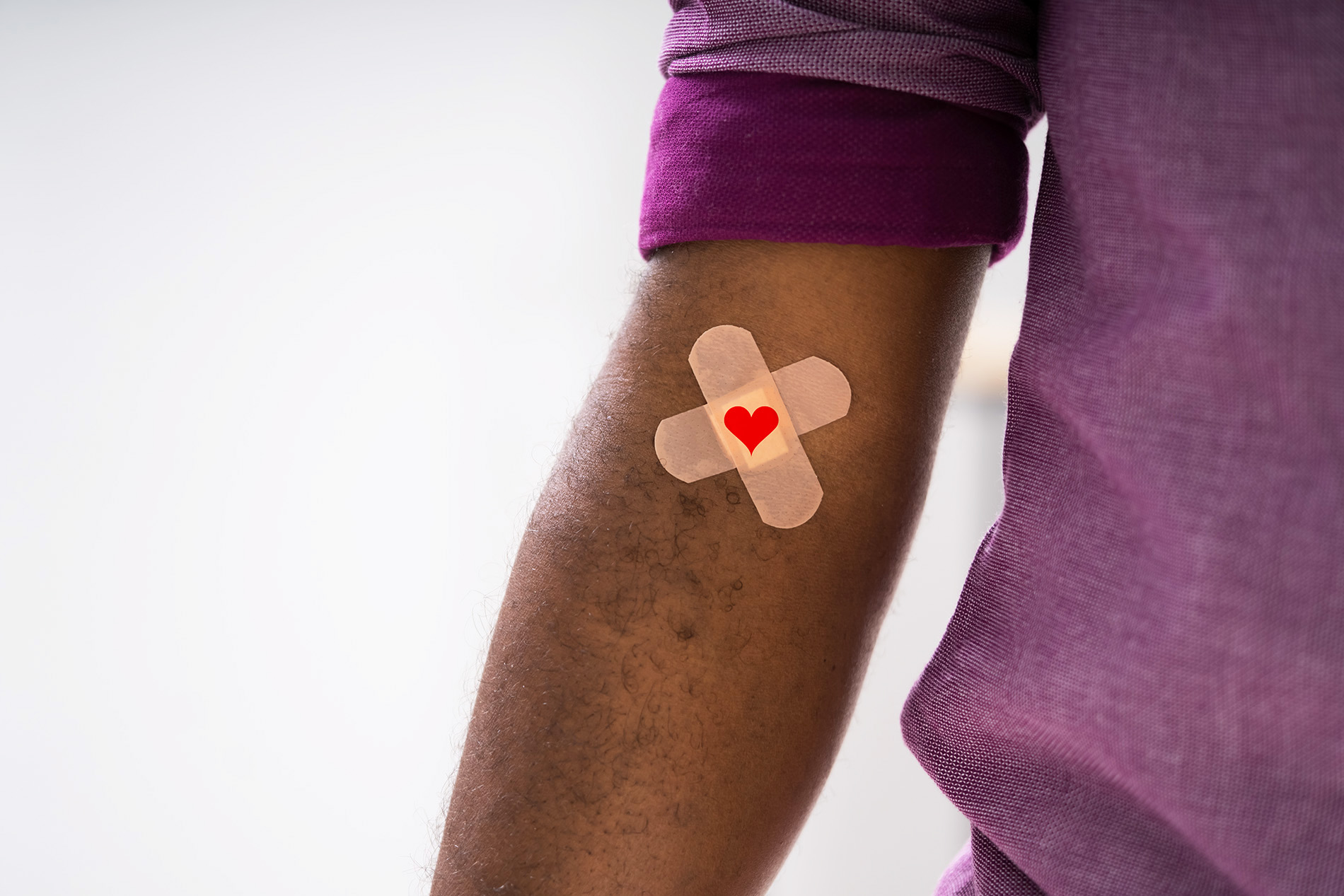 Black man in purple shirt with bandage on arm after donating blood