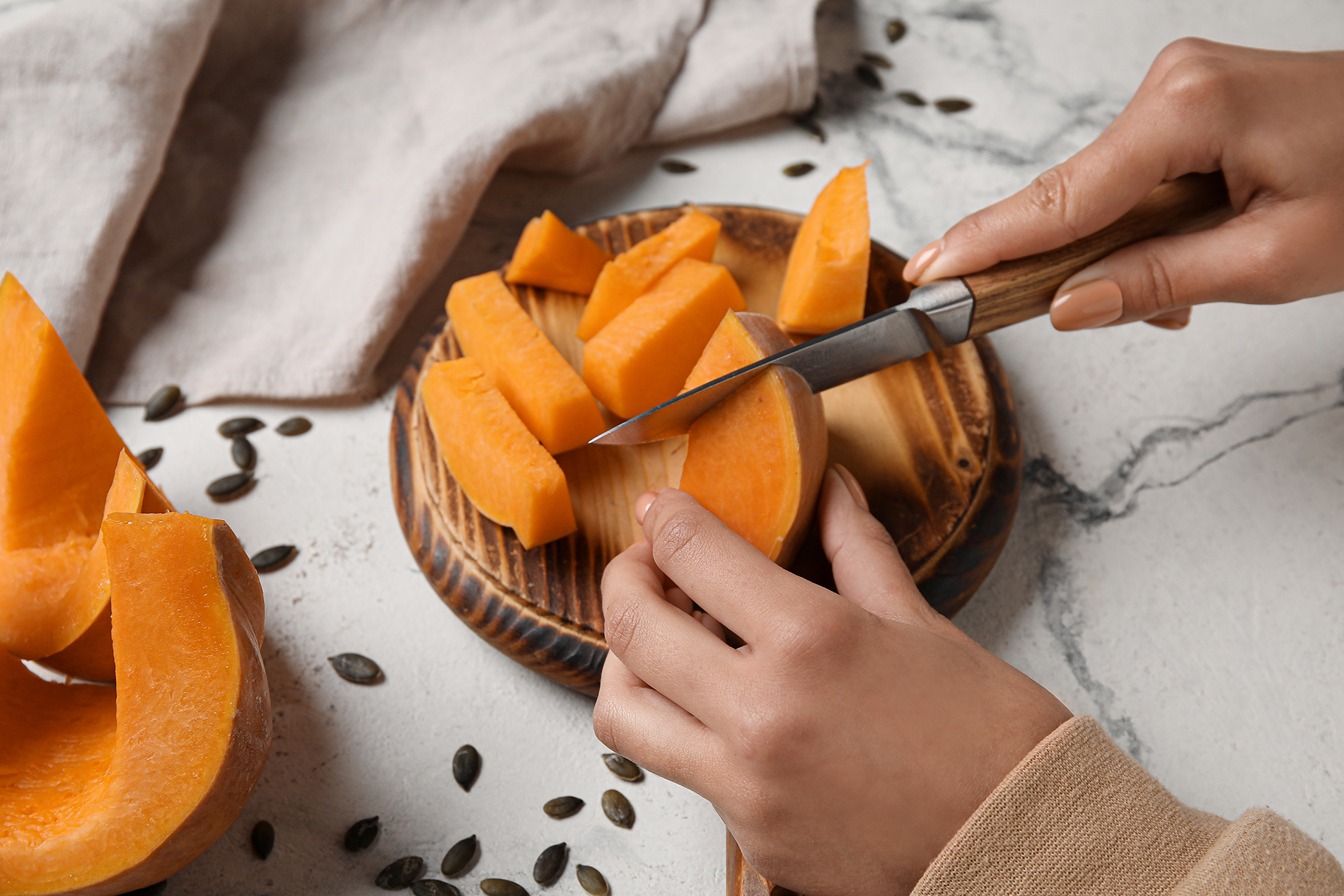 young black female's hands cutting pieces of pumpkin