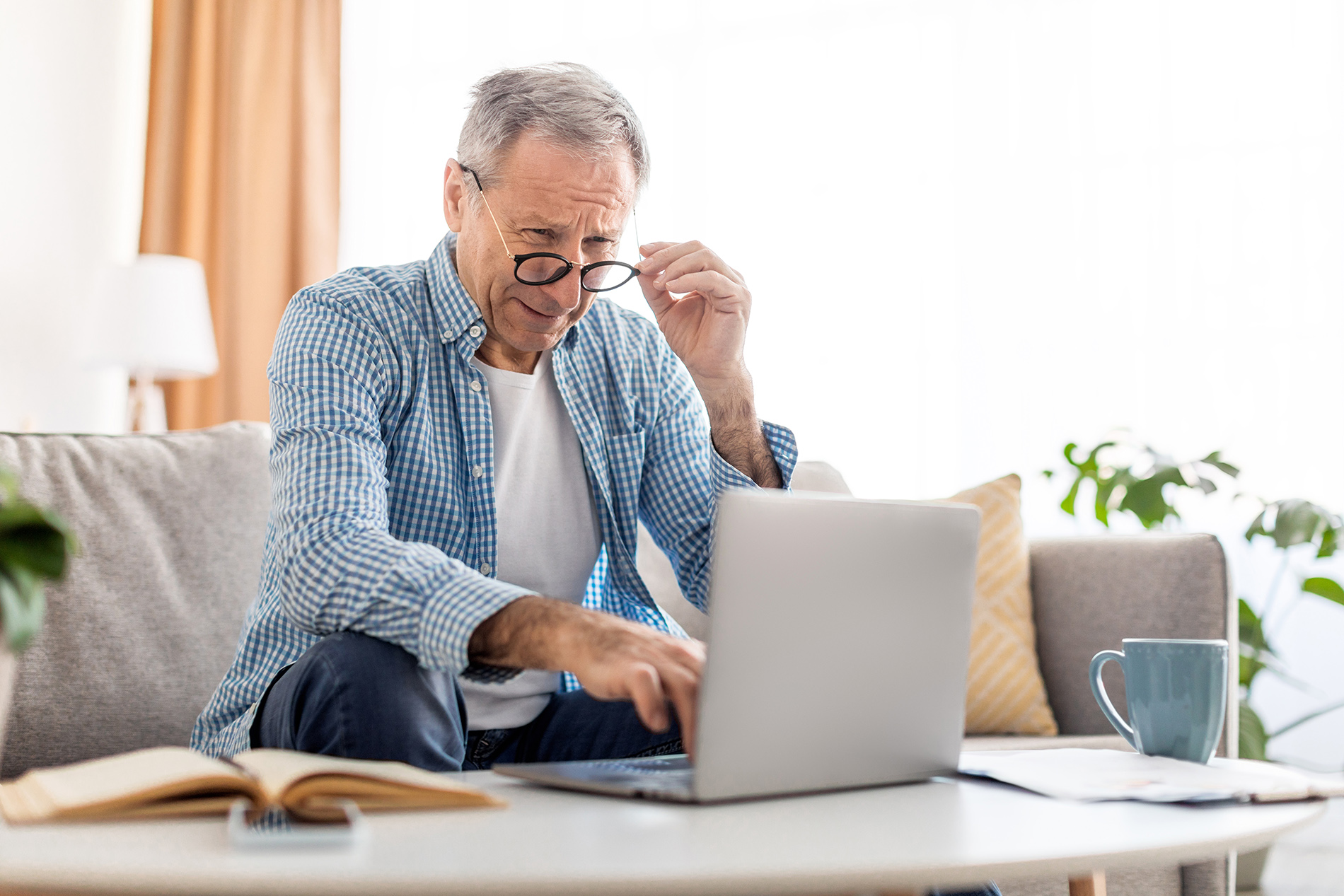 Older man squinting while looking at computer