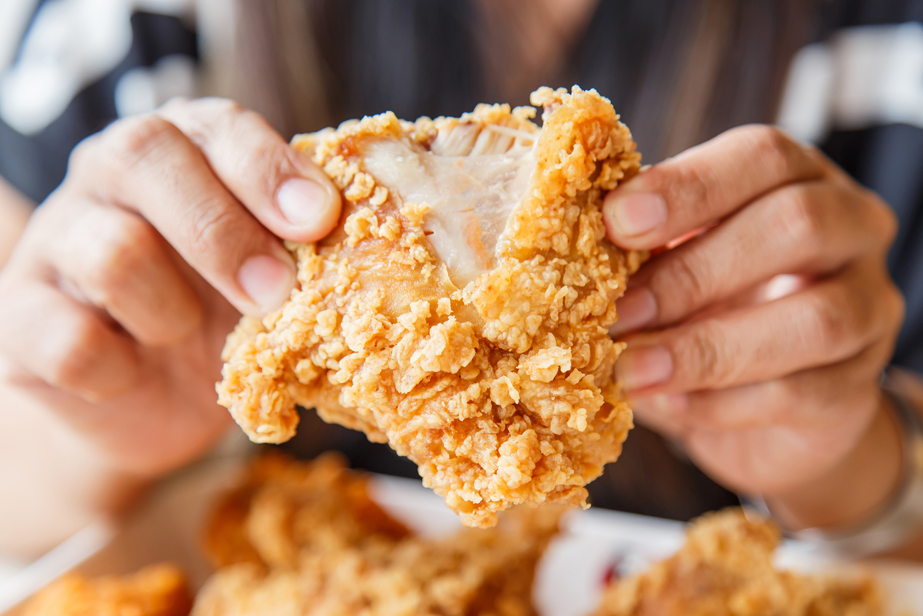 Man holding piece of fried chicken