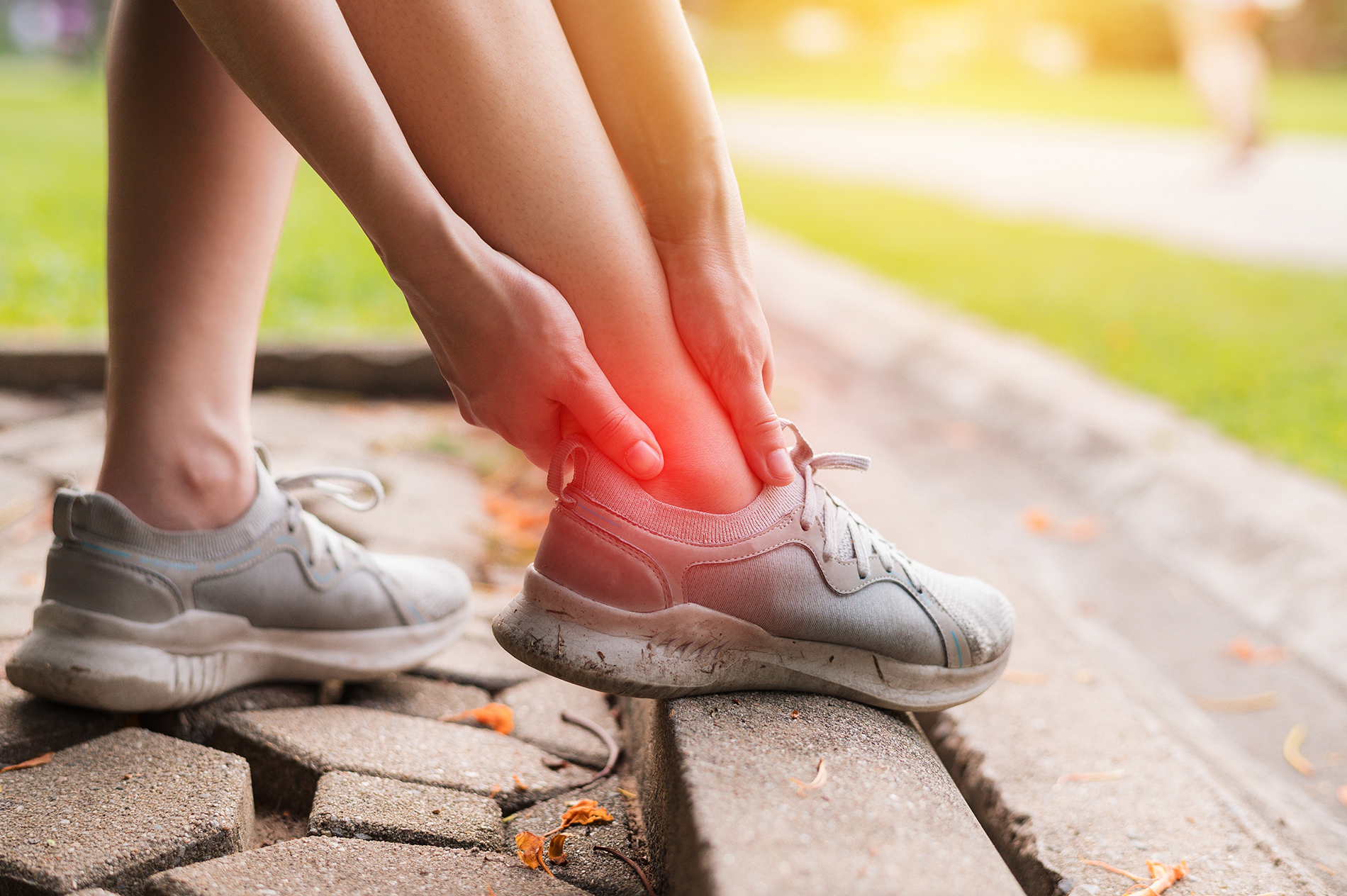 Young woman stepping off curb and twisting ankle