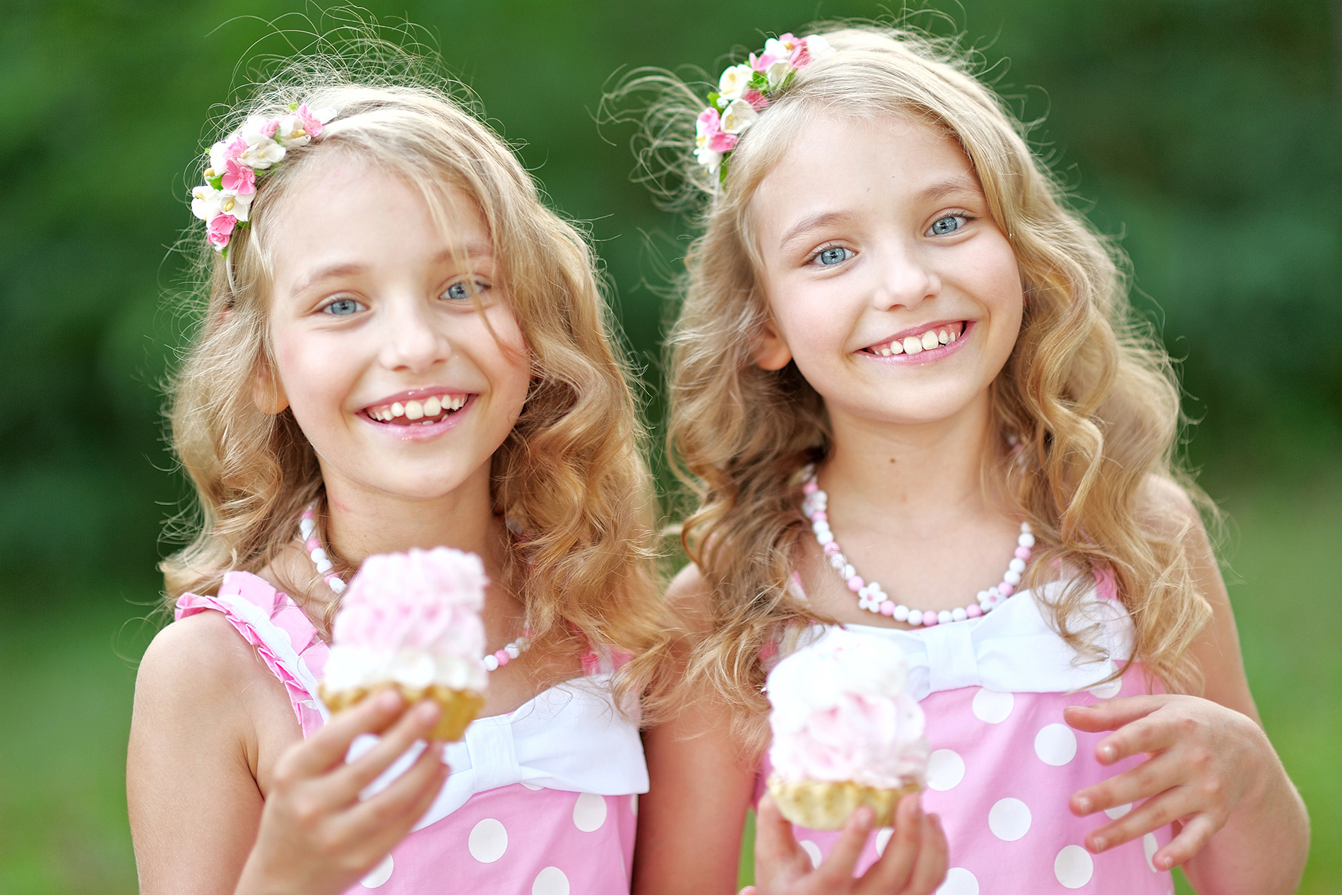 Twin girls wearing pink dresses with ice cream cones