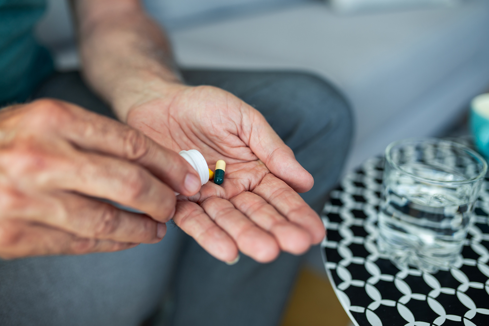 Man's hand pouring pills from medication bottle into his hand