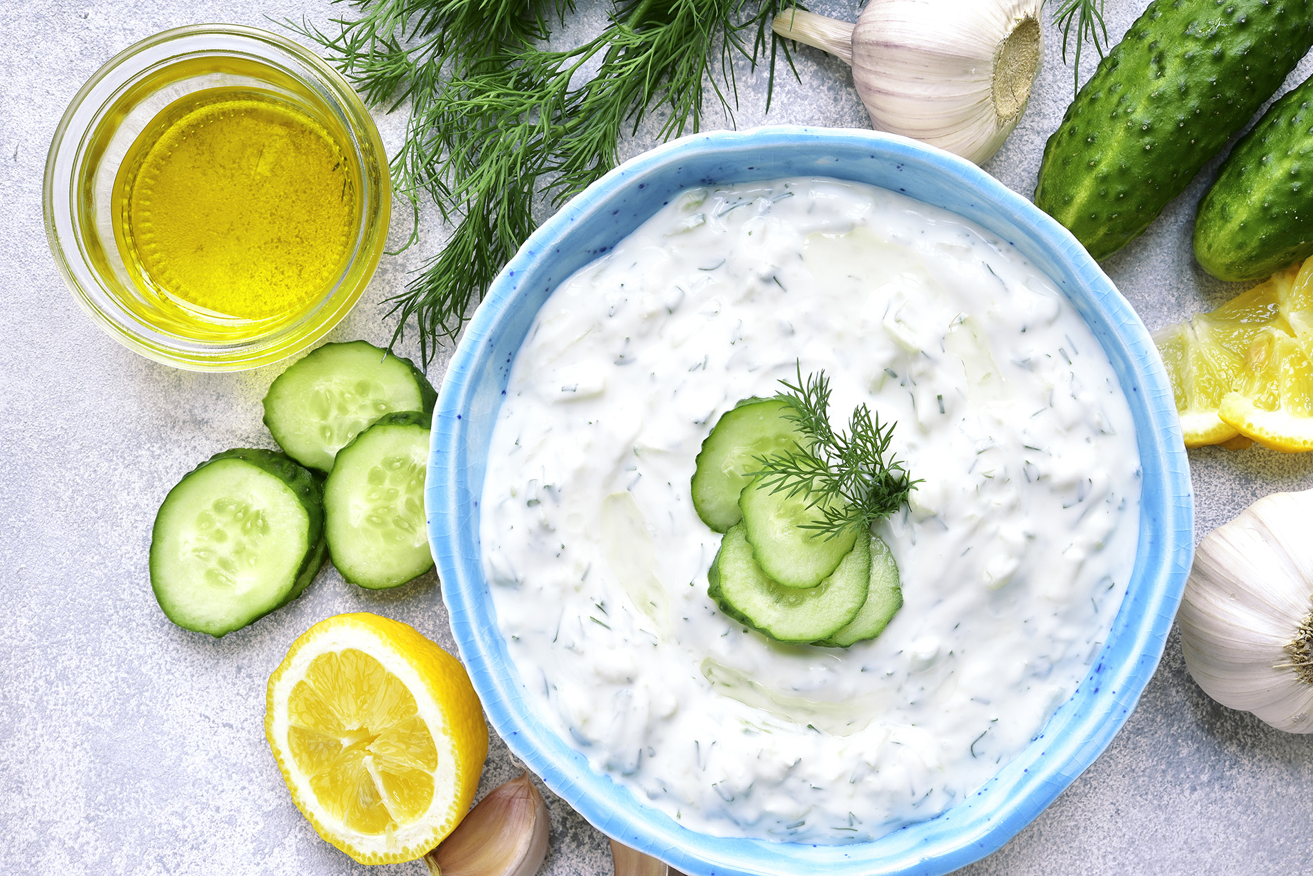 Bowl of Greek yogurt with cut lemons, cucumbers and crackers