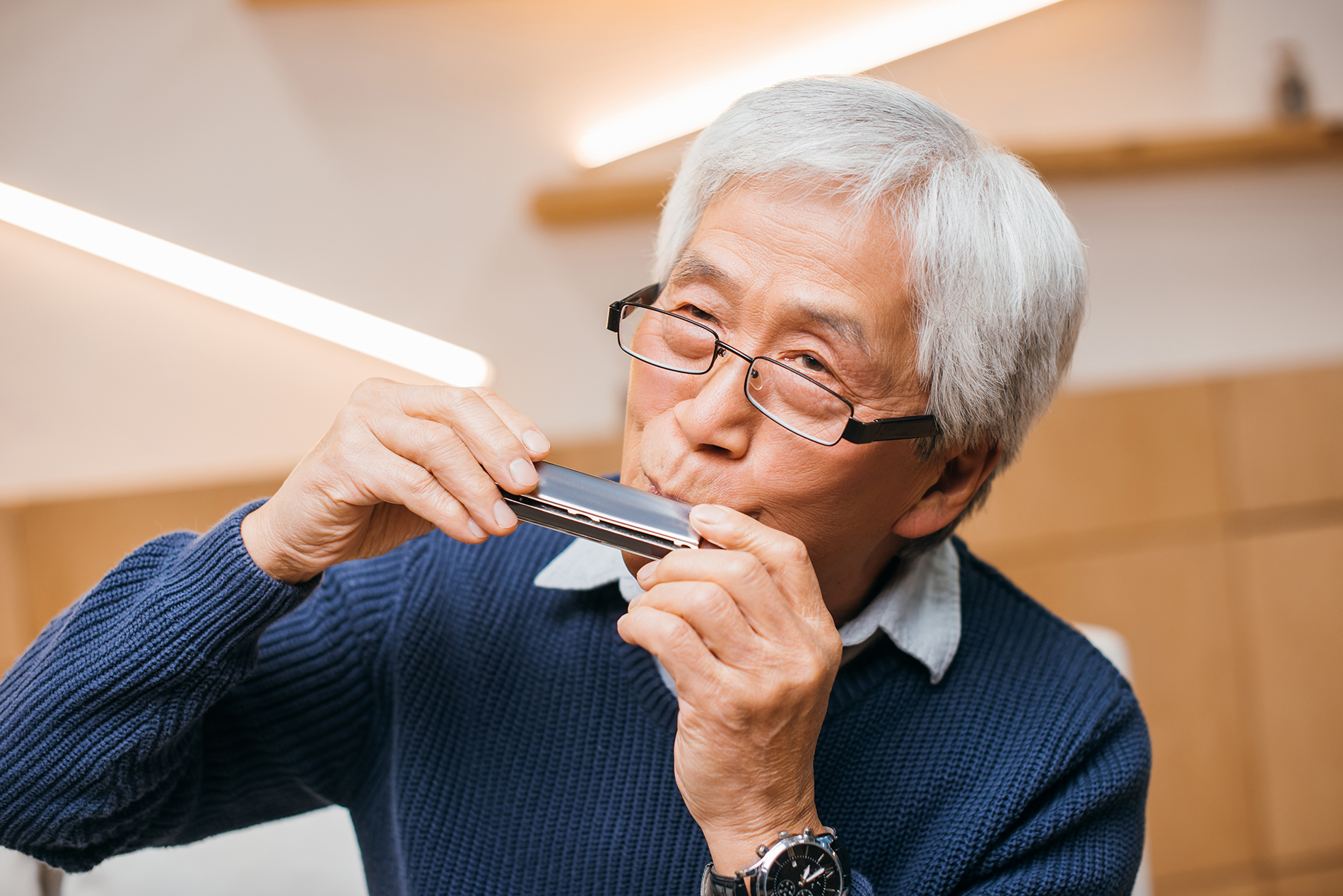 Older Asian man playing the harmonica