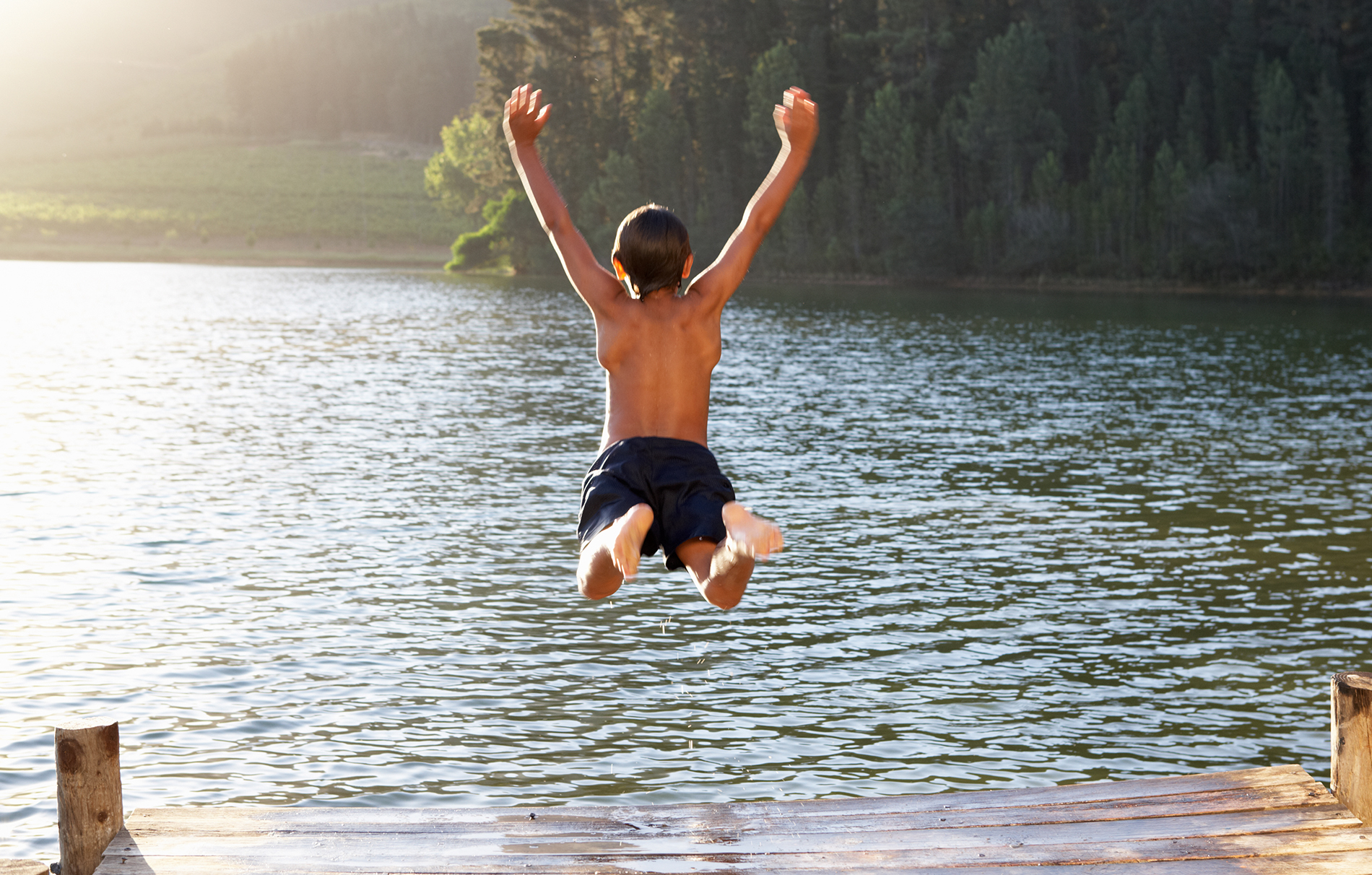 Boy jumping off dock into lake