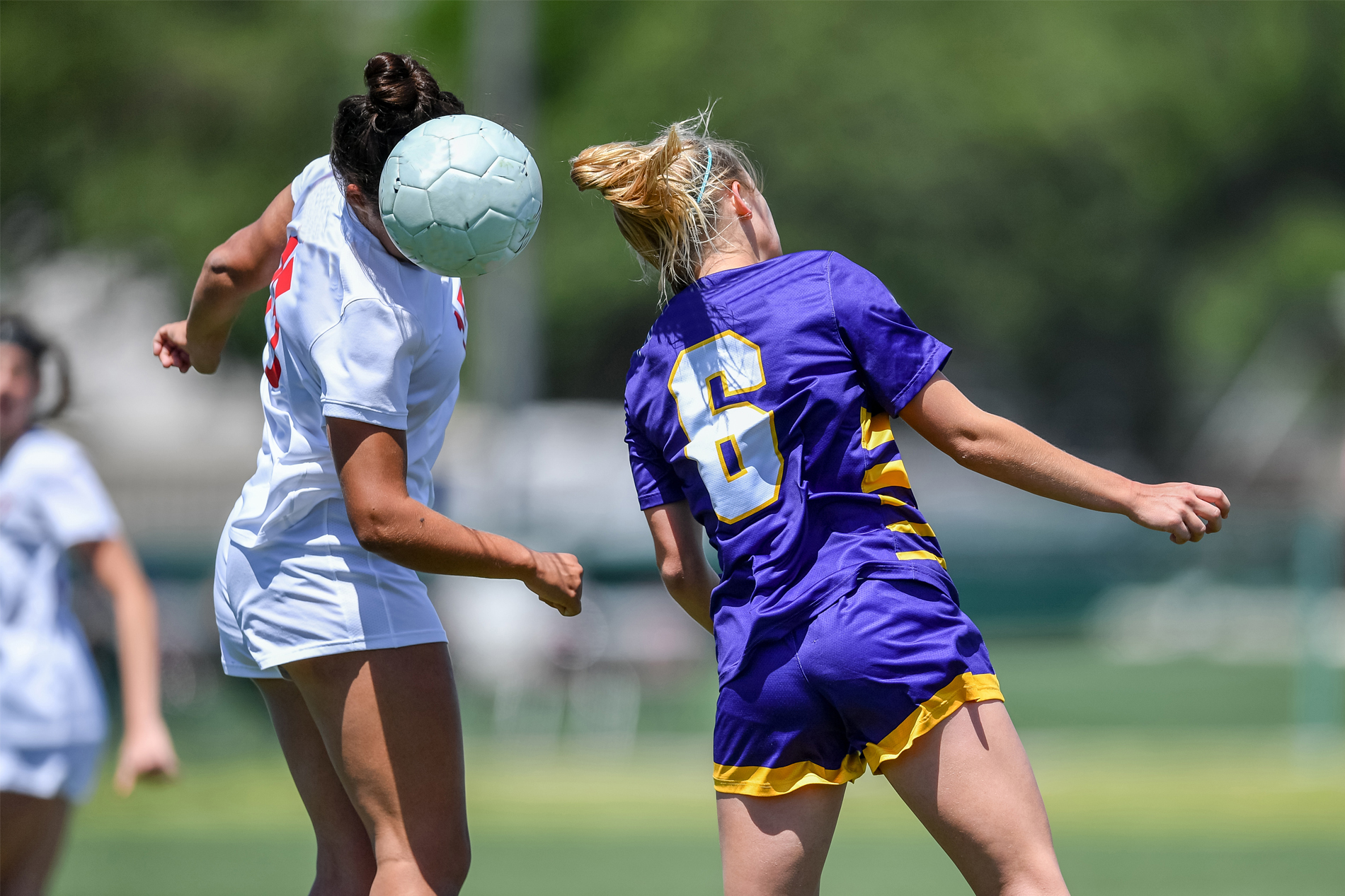 Two female soccer players heading the ball