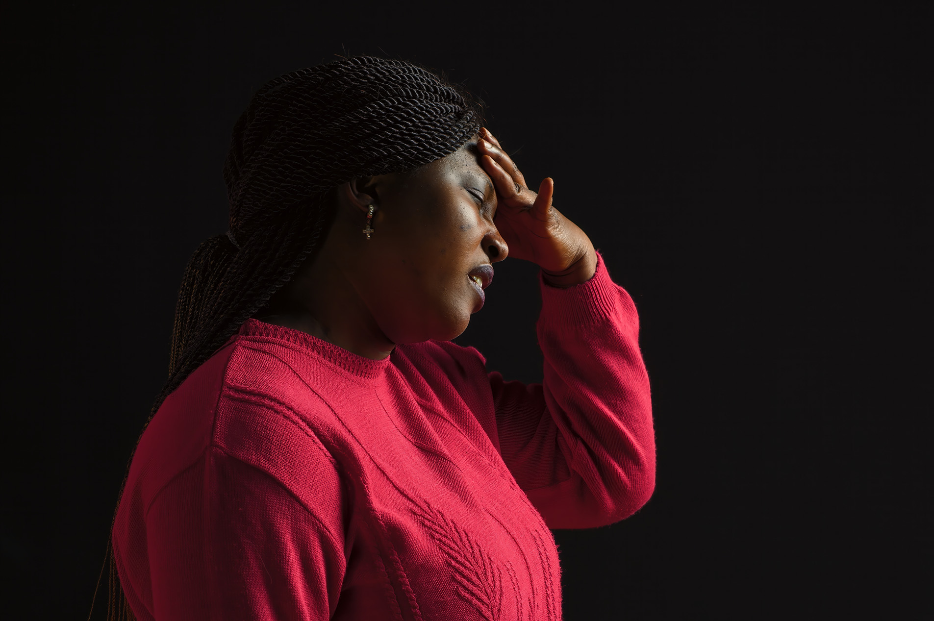 Overweight young black woman in red sweater with severe headache