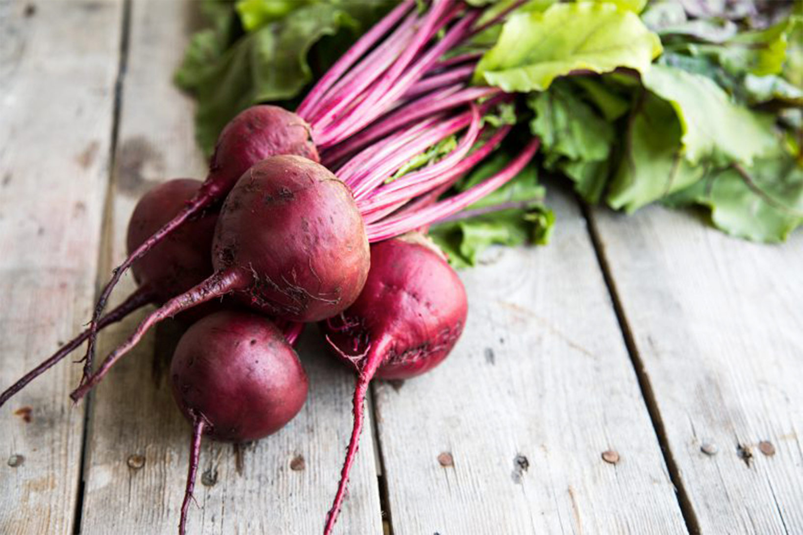 A bushel of beets on wood.