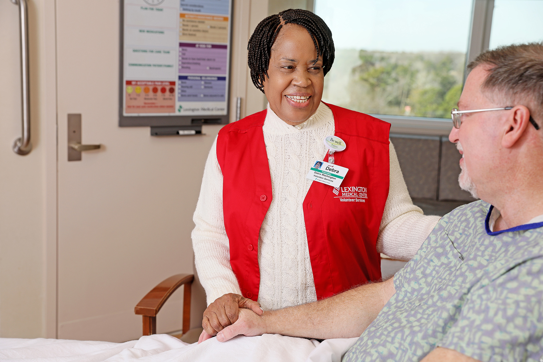 Female volunteer helping patient in his hospital bed