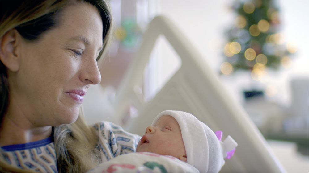 Woman smiling at her newborn in hospital bed