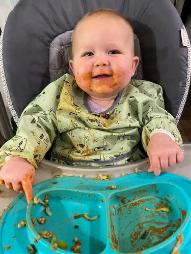 baby in high chair with food on face