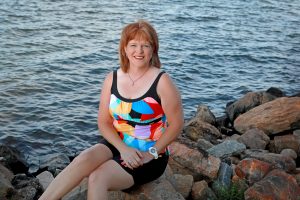 Karen Adkins, sitting on rocks by Lake Murray's shore in swimwear