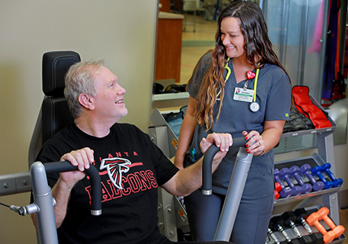 Patient exercising at Cardiac Rehabilitation while talking with nurse