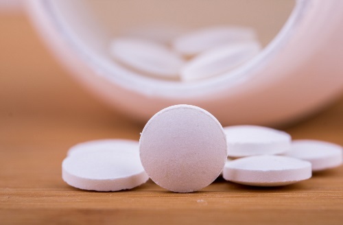 White pills pouring out of pill bottle