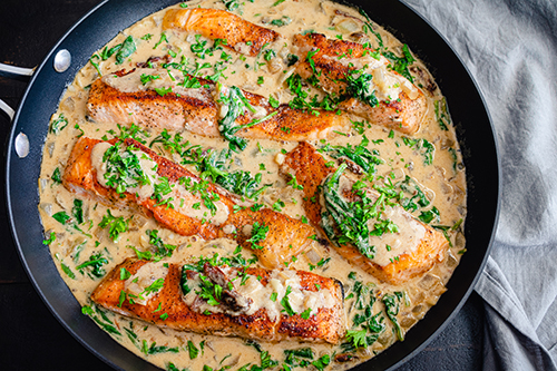 Creamy spinach and salmon cooking in skillet