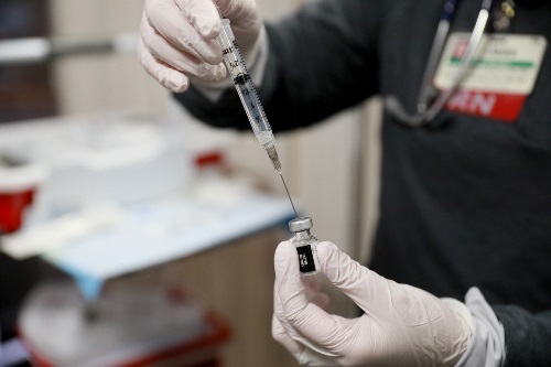 Nurse drawing vaccine from the vial into a syringe