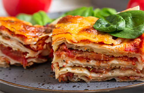 slices of tomato lasagna on a black plate